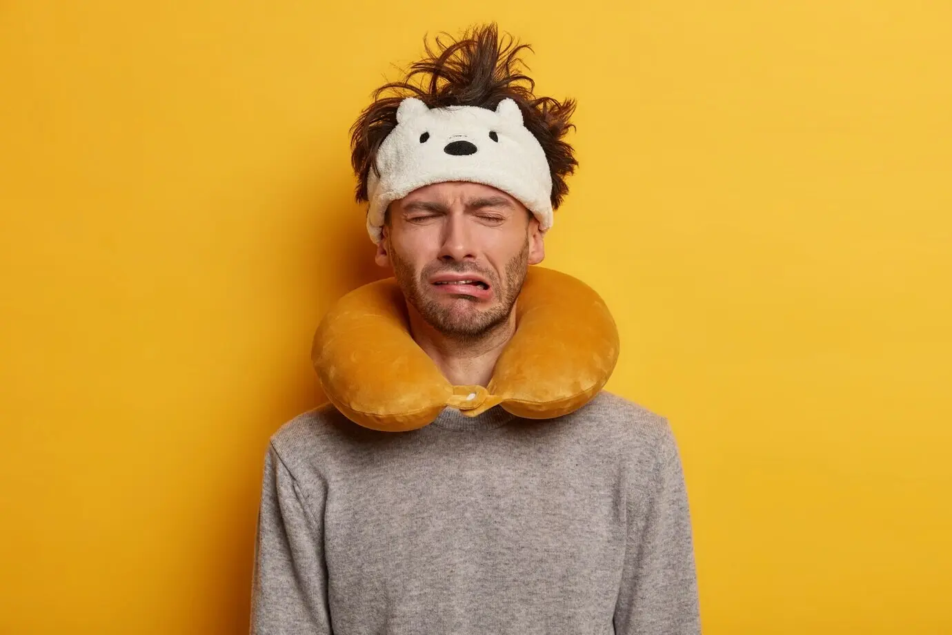 A male passenger is wearing a travel pillow for sleeping during the journey.